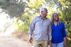 Two people holding hands walking on the road.